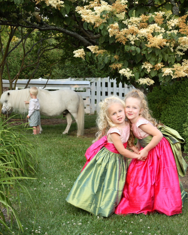 Children in silk dresses beside a pony